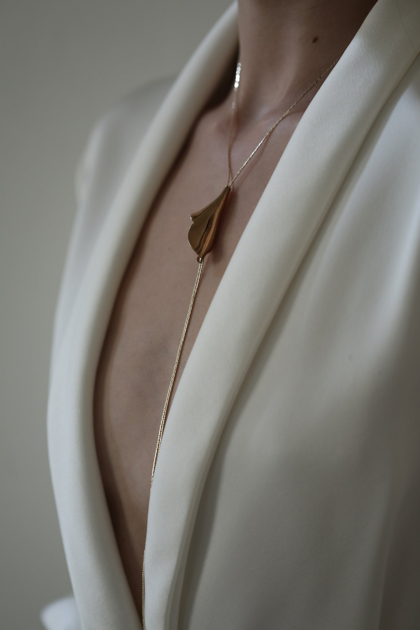 Front photo of bride wearing the floral Tula gold lariat necklace by AB Ellie paired with ivory blazer