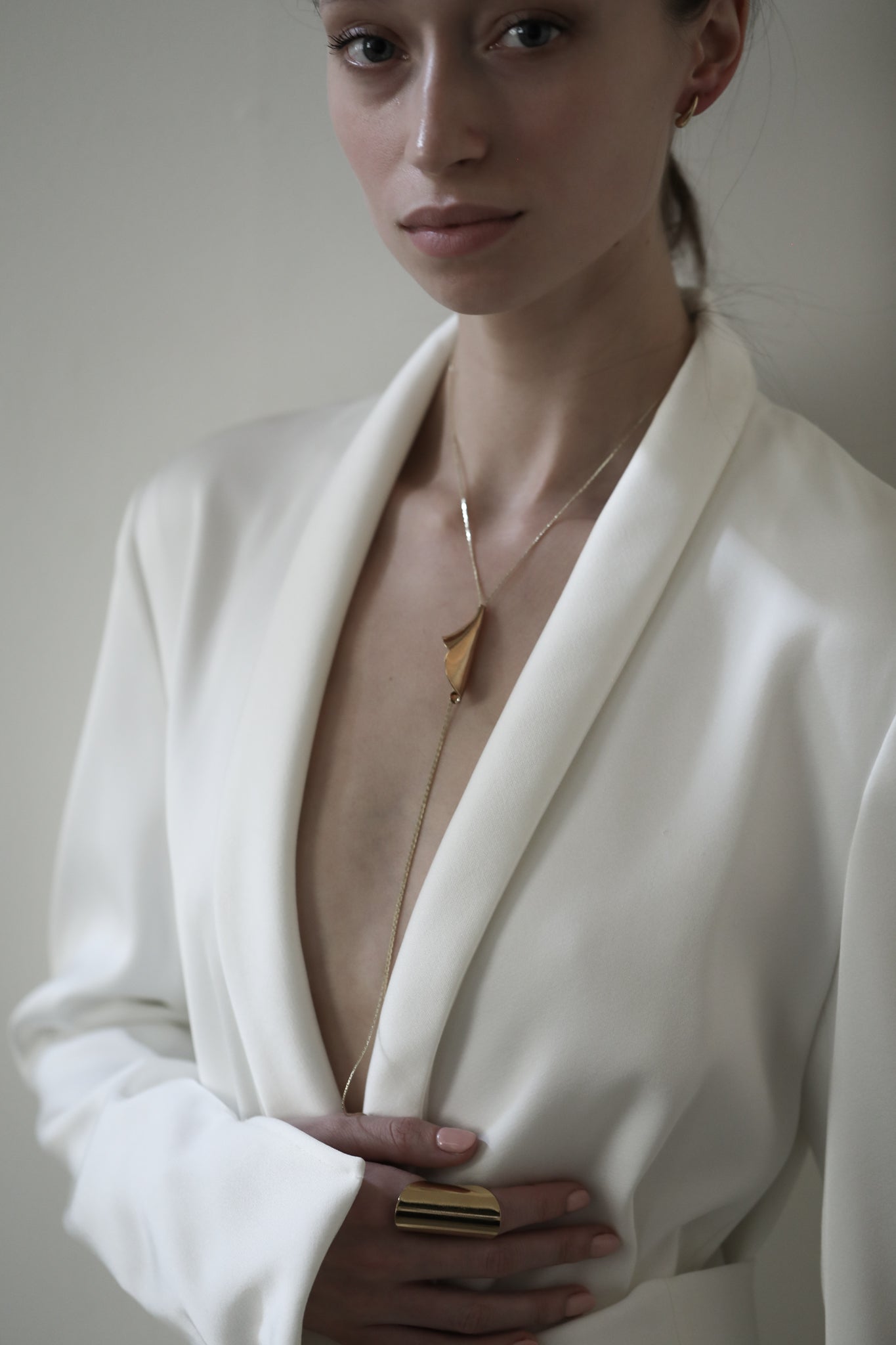 Front view photo of brunette bride wearing the Floral Tula gold lariat necklace by AB Ellie paired with an ivory blazer