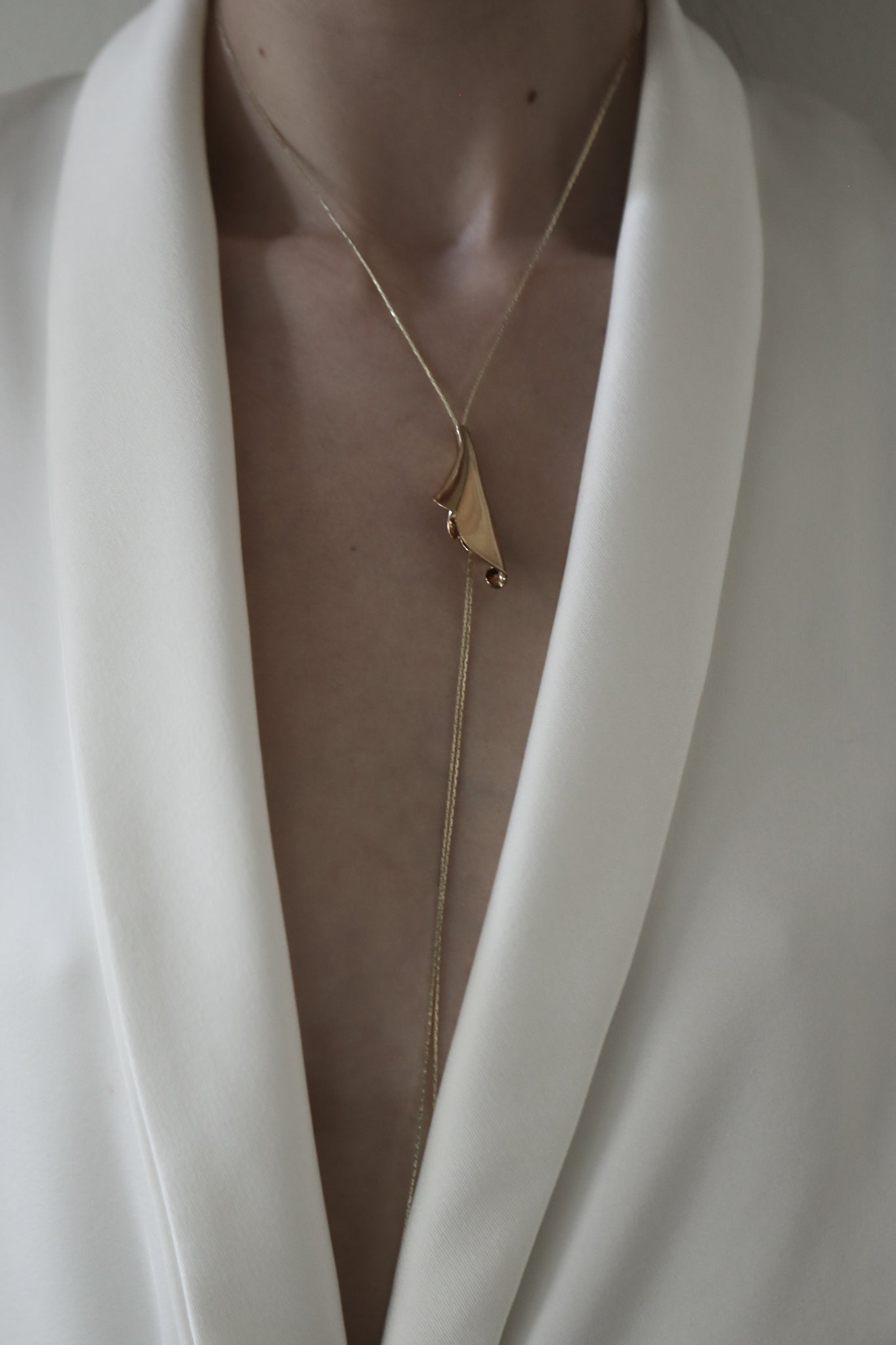 Close up photo of brunette bride wearing the Tula floral lariat necklace in gold by AB Ellie