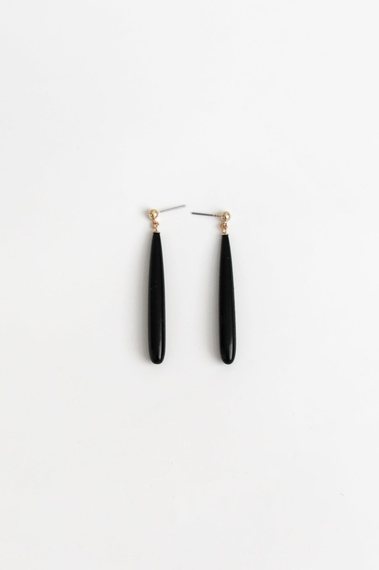 Flat vertical image of svelte black glass drop earrings by A.B. Ellie, on white background